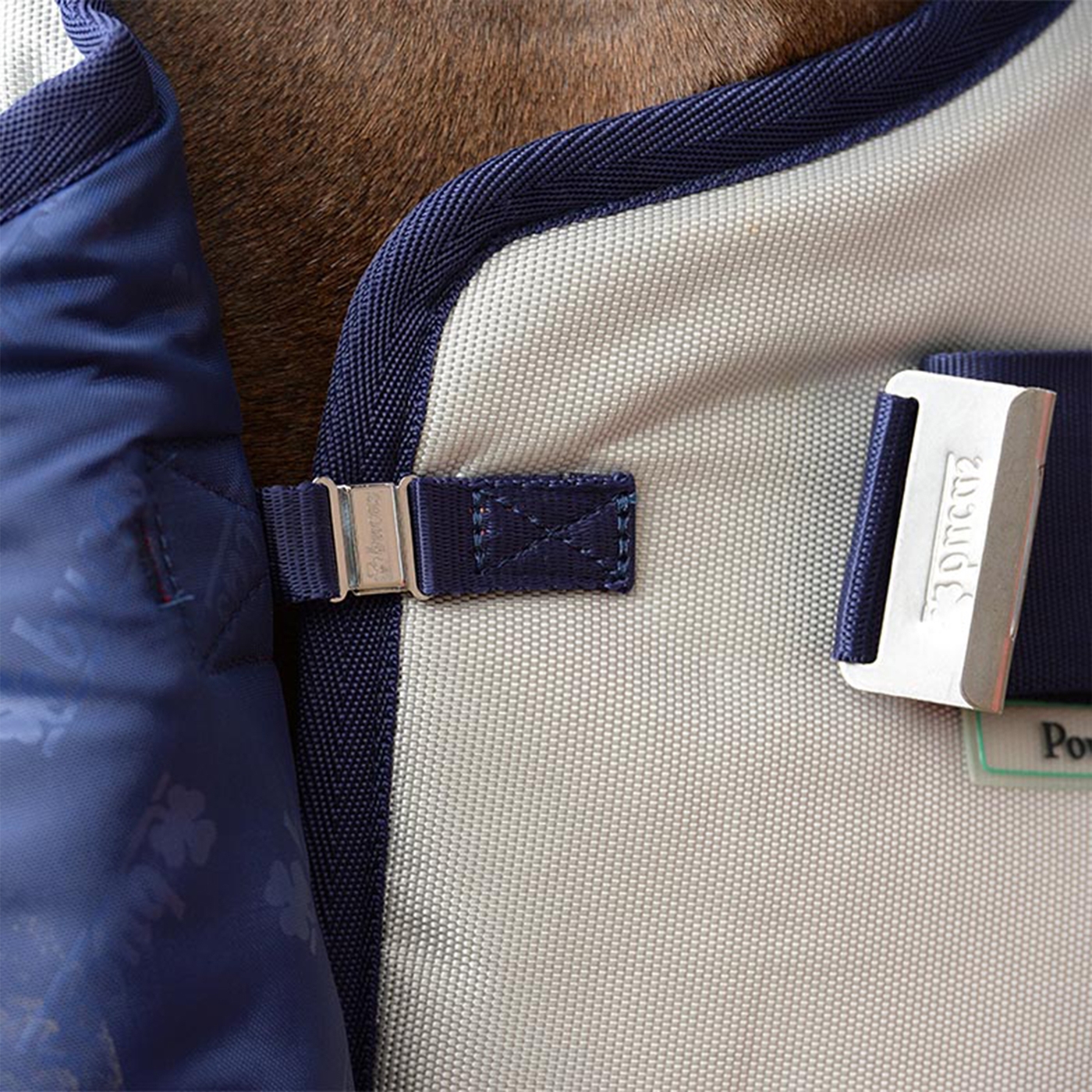 Doppelklicken zum vergrößern Nahaufnahme der Bucas Bucas Power Turnout Medium 150 g, 125 cm Winterdecke für Pferde aus blau-weißem Stoff mit Metallverschluss und Schnalle.