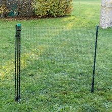 Die VOSS.farming Tür für Elektrozaunnetze, elektrifizierbar, 120cm von VOSS.farming ist auf einer Wiese mit Bäumen und Büschen im Hintergrund installiert.