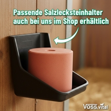 Ein VOSS.vital Leckstein - MineralLine Salzleckstein mit Spurenelementen (5kg) von S.I.N. Hellas ist in einem Salzlecksteinhalter an einer Holzwand montiert, darüber steht ein deutscher Text.