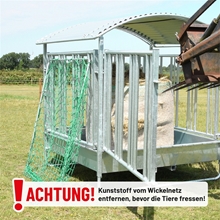 VOSS.farming Rahmen für Futtersparnetz für quadratische Heufuttertröge, bestehend aus einem verzinkten Metallrahmen mit einem daran befestigten grünen Futtnetz und einem deutschen Warnhinweis, der darauf hinweist, das Kunststoffnetz vor der Verwendung zu entfernen.