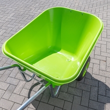 Die LandXpert-Schubkarre – 250 Liter, grün, mit doppelt bereiften Luftreifen und einer robusten Kunststoffwanne – steht leer auf grauem Pflaster in der Sonne.