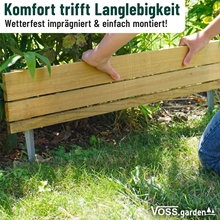 Zwei Hände verlegen den VOSS.garden Steckzaun 75x18cm Beeteinfassung aus Holz mit Metallpfählen als Rasenbegrenzung neben Gras und Pflanzen. Der deutsche Text hebt die Langlebigkeit und den Komfort des Produkts hervor. Marke: VOSS.garden.