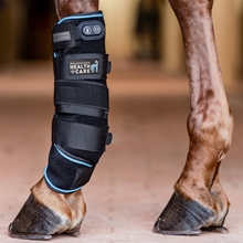Ein Pferdebein mit dem Waldhausen Health + Care Gamasche von Waldhausen, einem schwarz-blauen Therapiestiefel mit Klettverschlüssen, der Kühl-, Wärme- und Vibrationsfunktionen bietet.