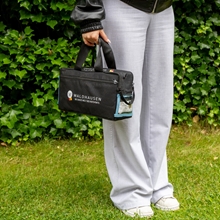 Schwarze Waldhausen Health + Care Gamasche-Tasche mit Tragegriffen, Logo und deutscher Flagge, isoliert auf weißem Hintergrund dargestellt.