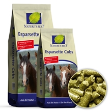 Zu sehen sind zwei Säcke „NATURE’S BEST Esparsette Cobs“ der EQUOVIS GmbH (getreidefrei, melassefrei, Heuersatz-Raufutter für Pferde), auf deren Verpackungen jeweils zwei Pferde abgebildet sind. In einer runden Einblendung ist eine Nahaufnahme von grünlich-braunen Futterpellets zu sehen.