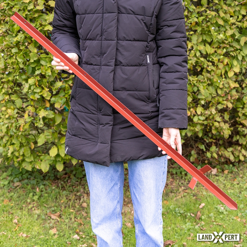 Großansicht der Bildergalerie Eine Person, die einen 10er-Pack LandXpert Winkelstahlpfähle 115 cm, 2 mm, rot in der Hand hält; dabei handelt es sich um lange rote Metallwinkelpfähle mit vorgebohrten Löchern.